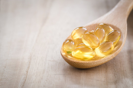 Fish oil capsules on wooden spoon