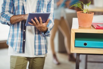 Mid section of businessman using digital tablet in office