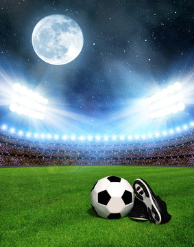 Soccer ball and shoes in grass, soccer stadium with the dright lights