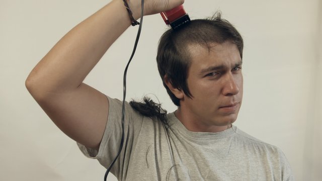 Guy shaves off hair on the head using of the electric shaver