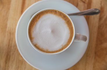 A cup of coffee with in a white cup on wooden background