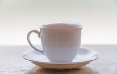 A cup of coffee with in a white cup on wooden background