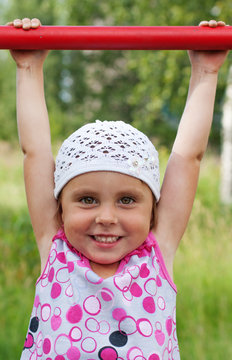 The little girl clings to crossbar