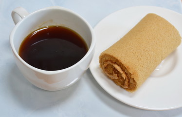 cake roll on dish and black coffee