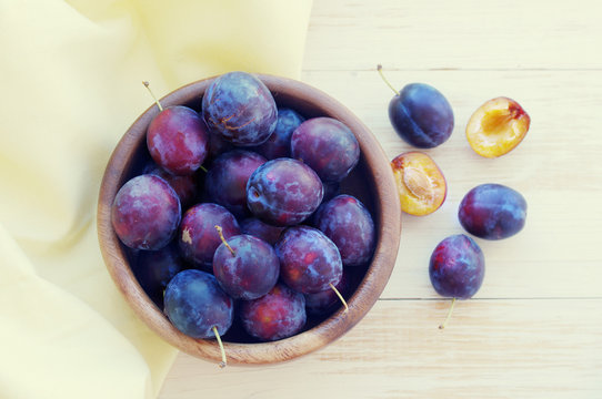 Fresh juicy plums in a wooden round plate. Crop of plums
