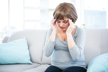 Pregnant woman having headache on couch 