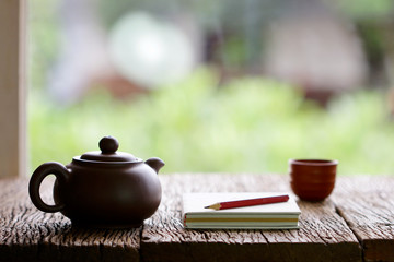 vintage old teapot clay cup and notebook  on wooden table