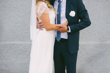 Beautiful bride hugs groom on a gray background, wedding, marriage, relationship, lifestyle