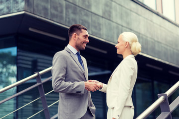 smiling businessmen shaking hands on street