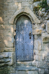 Fototapeta na wymiar Ancient wooden door in old stone castle wall, Knaresborough, North Yorkshire, UK