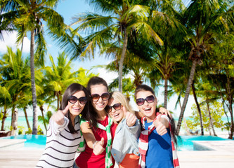 happy teenage girls showing thumbs up on beach