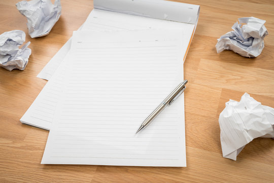 White note book paper with pencil and crumpled paper on a wooden