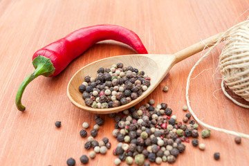 Colorful pepper in a wooden spoon over rustic wooden background
