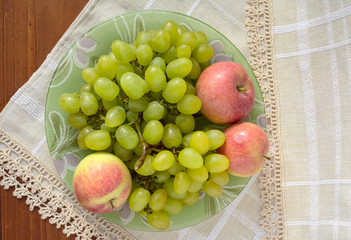 Green grapes and red apples on a plate