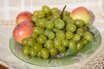 Green grapes and red apples on a plate