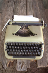 Old typewriter with blank paper on wooden background