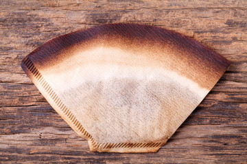 Coffee filter with brewed coffee on wood background