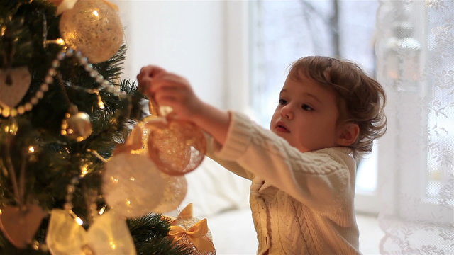 Cute little girl decorates the Christmas tree.