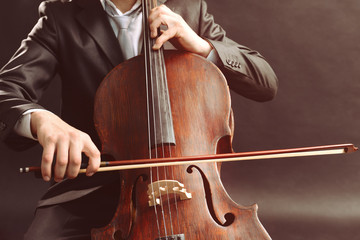 Man playing on cello on dark background