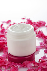 Cosmetic cream surrounded by rose hip petals