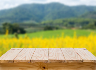 Wood table with blur yellow fields background