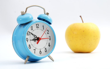 blue alarm clock and apple  on a white background