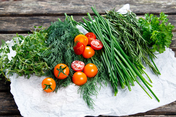 Fresh Tomatoes and Green Vegetables. Onion, Dill, Rosemary, Parsley, Chives and thyme. on old wooden table.