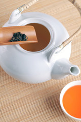 Chinese white teapot and tea cups on the wooden trivet 