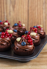 Chocolate cupcakes decorated with chocolate cream and summer ber