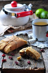homemade biscotti with dried cranberries and lime, with a cup of green tea kettle on the wooden table. rustic style. selective focus. 