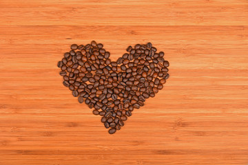 Heart shaped coffee beans over bamboo wood background