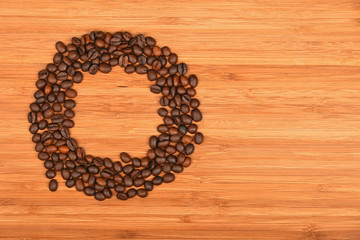 Circle shaped coffee beans over bamboo wood background
