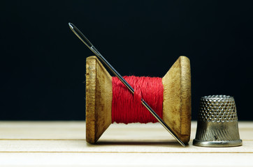 Old spool of thread with needle closeup. Tailor's work table. textile or fine cloth making.