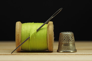 Old spool of thread with needle closeup. Tailor's work table. textile or fine cloth making.