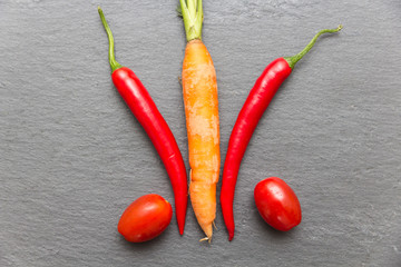 Chilis mit Karotte und Tomaten auf grauer Schieferplatte