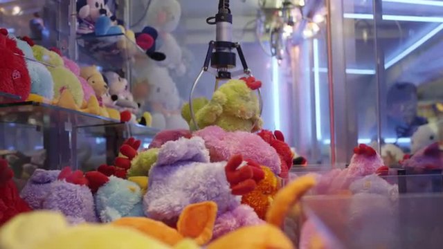 Low angle slow motion shot of claw dropping stuffed toy in arcade machine / Paris, France