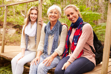 Fototapeta premium Three generations of women sitting in a forest, portrait