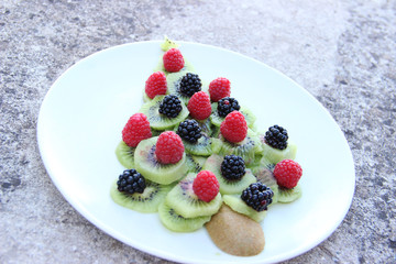 Foodart avec un sapin en kiwis, framboises et mûres