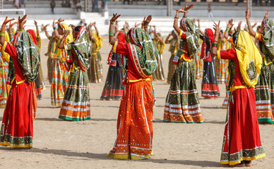  Indian girls in colorful ethnic attire dancing at Pushkar fair,