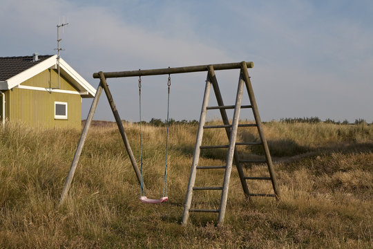 Childhood Memories. Play swings frame the distant sand dunes. There are no fences and the subtext is of summer, freedom and childhood adventures.