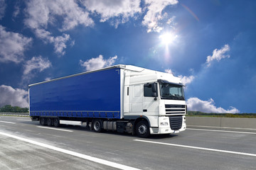 Fototapeta na wymiar fahrender LKW auf einer Autobahn transportiert Güter // truck on highway - shipping and logistics