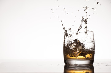 Ice splash into whiskey or brandy