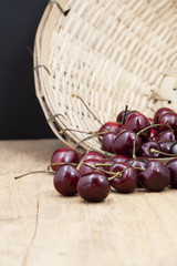 
Juicy ripe cherries in bamboo basket on old wooden table top.
