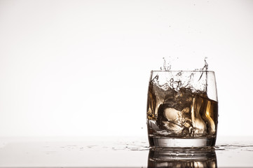 Ice splash into whiskey or brandy