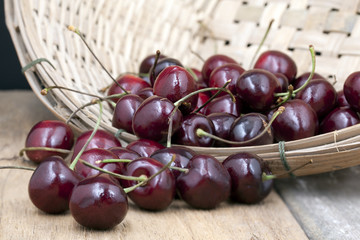 
Juicy ripe cherries in bamboo basket on old wooden table top.