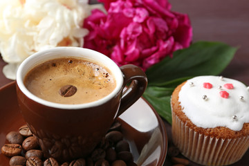 Composition with cup of coffee, muffins and peony flowers on wooden background