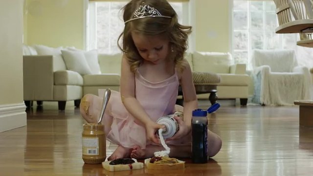 Medium shot of ballerina girl spraying whipped cream on bread / Cedar Hills, Utah, United States