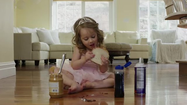 Medium shot of ballerina girl eating sandwich on floor / Cedar Hills, Utah, United States