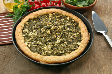 Open pie with spinach and tomato cherry on table close up