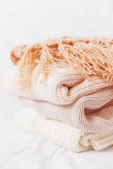 Pile of beige woolen clothes on a white background. Warm knitted clothes.